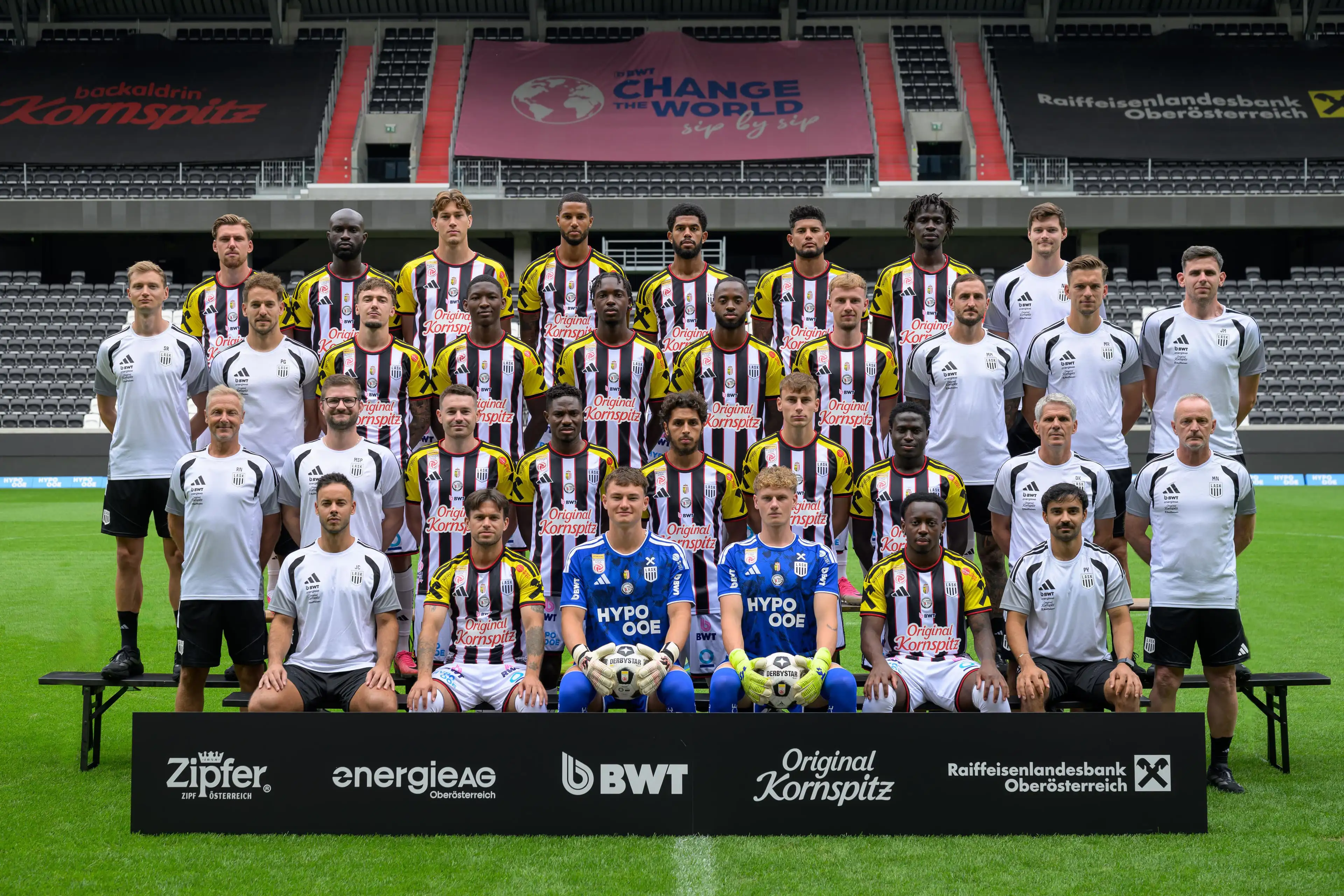 Mannschaftsfoto des LASK mit Spielern und Betreuerteam auf dem Fußballplatz im Stadion.