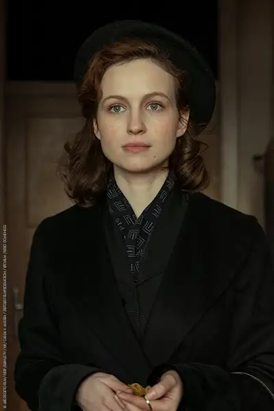 Diana Dulniková als Jitka Modrá, eine junge Frau in 40er Jahre Mantel und Hut.