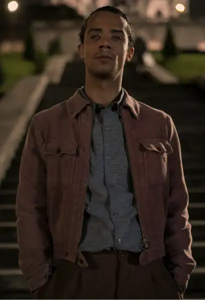 Jacob Anderson als Louis de Pont du Lac in Interview with the Vampire, er trägt eine braune Jacke, ein graues Hemd und eine dunkelbraune Hose.
