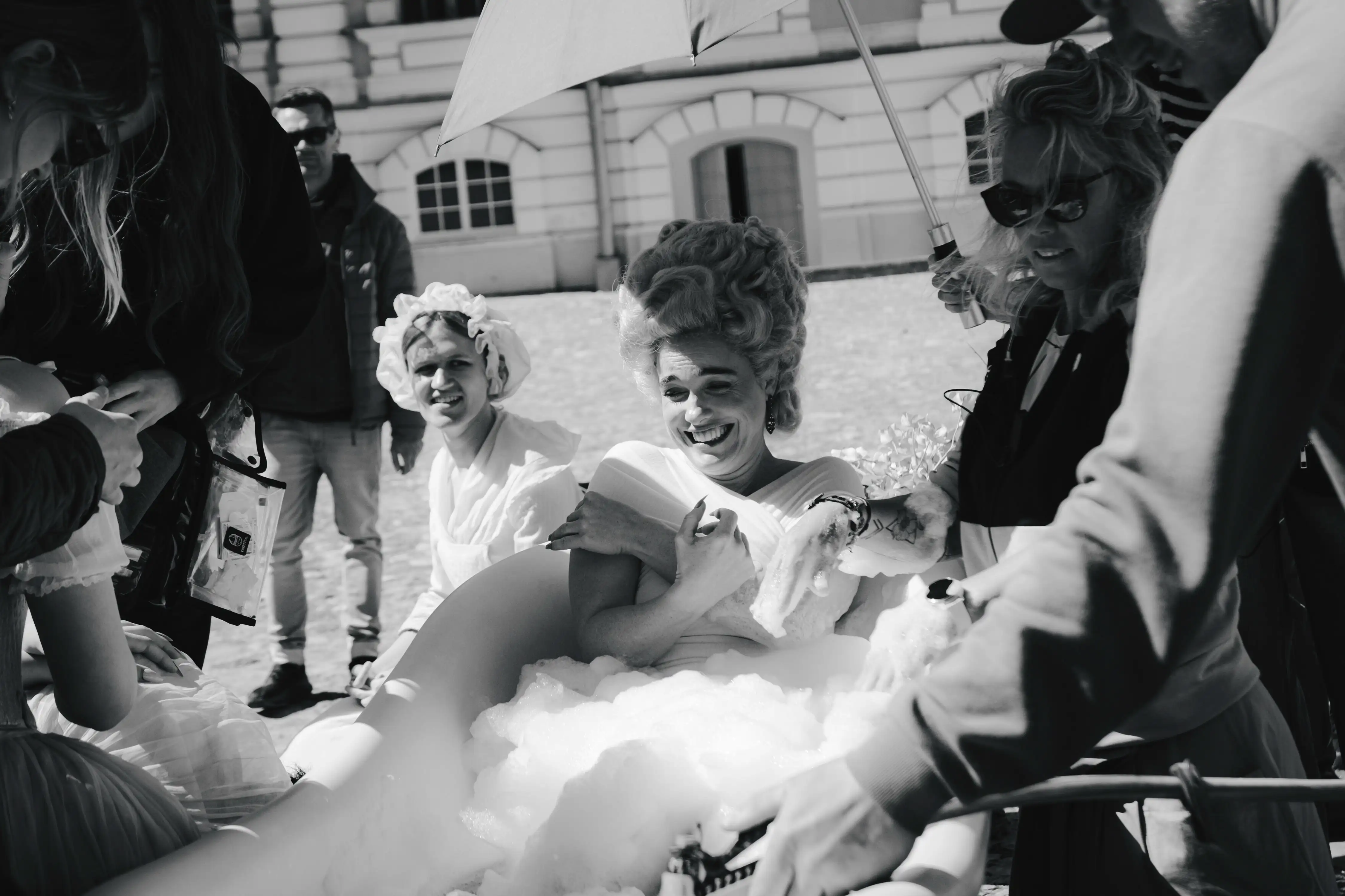Behind the Scenes Foto von Mozart/Mozart. Verena Altenberger in schwarz-weiß in einer Badewanne sitzend, umgeben von Crew.