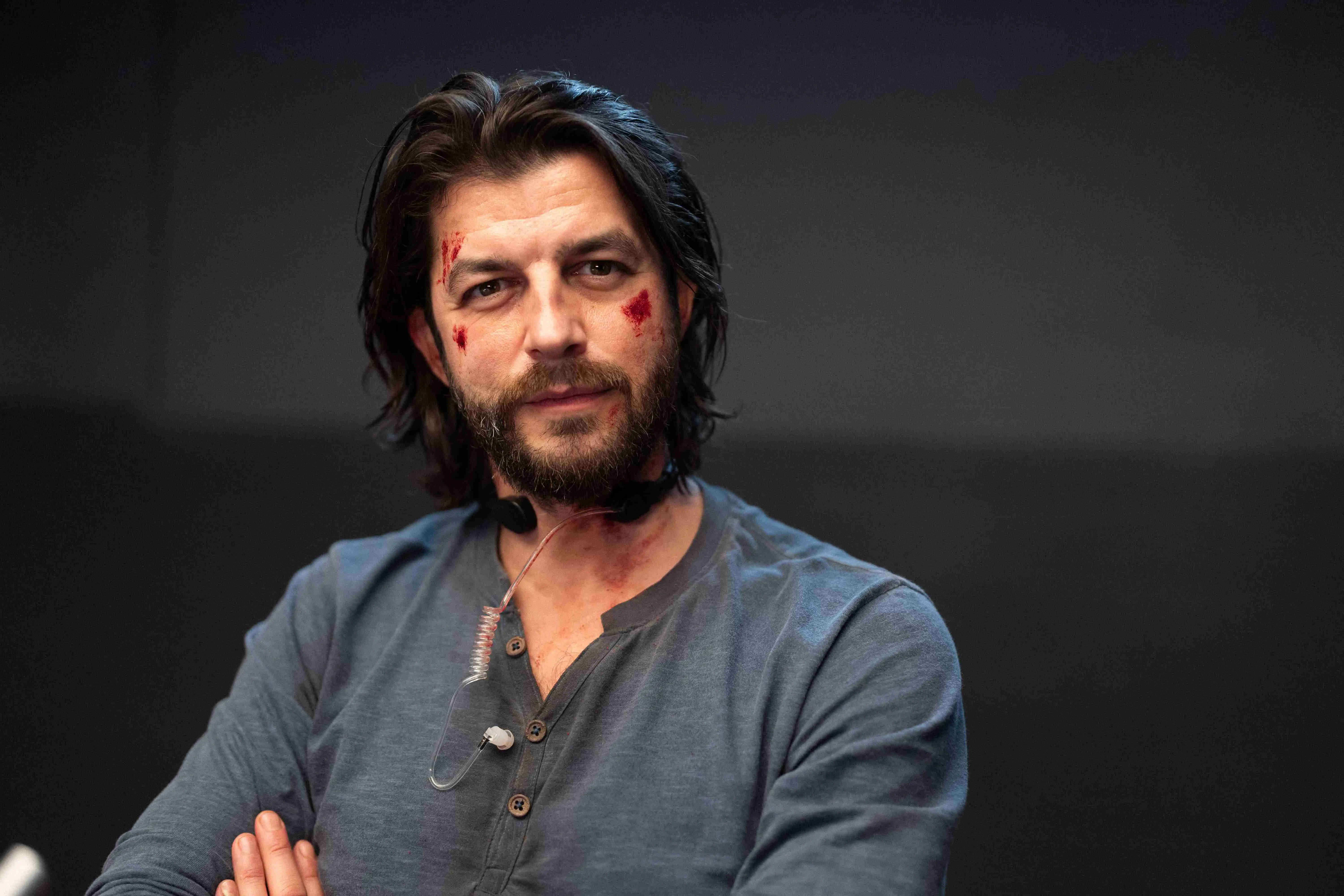 Otto Jaus als Eddi Kovac in Neo Nuggets, mit verschränkten Armen und ernstem Blick in einer dunklen Szene des österreichischen Action-Comedy-Films.