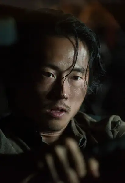 Steven Yuen als Glenn in The Walking Dead. Er sitzt im dunkeln in einem Auto.