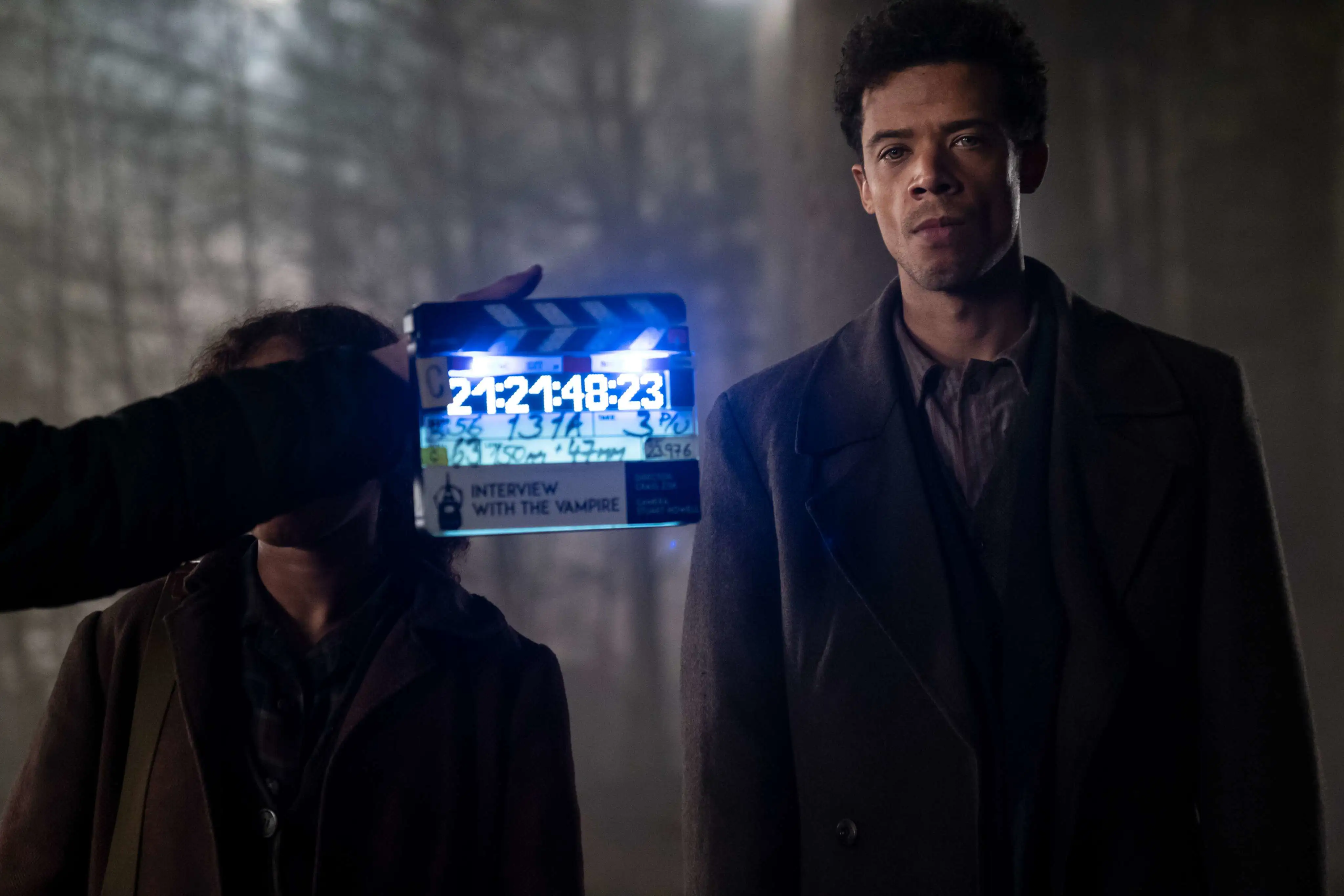 BTS Foto Interview with the Vampire. Jacob Anderson in einem grauen Anzug, eine Filmklappe ist links neben ihm zu sehen,