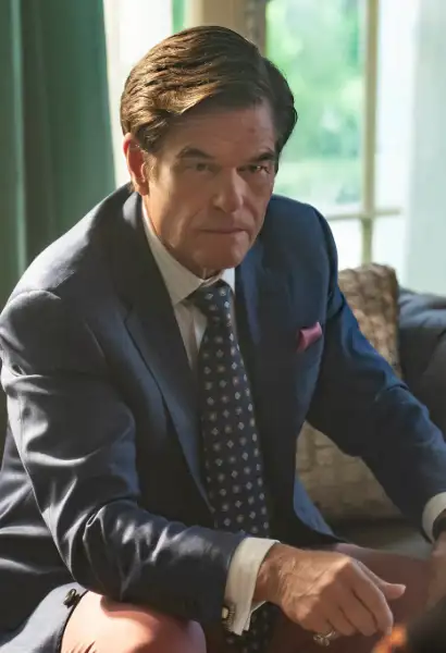 Harry Hamlin als Cortland Mayfair in Mayfair Witches. Er sitzt auf einer Couch, trägt einen Blauen Anzug.