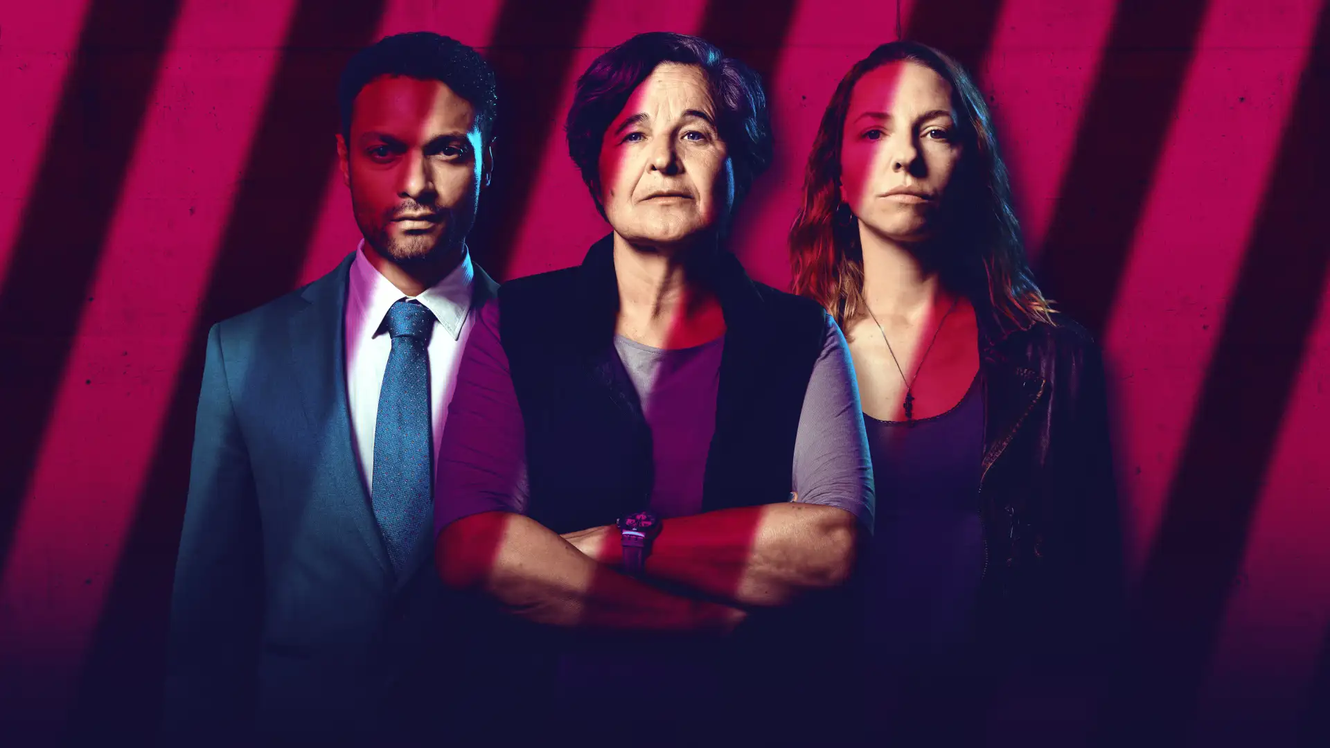 Das Bild zeigt Maria Hofstätter im Zentrum mit verschränkten Armen, links hinter ihr steht ein Mann im Anzug mit dunklen Haaren und Bart, rechts steht eine Frau mit langen dunkelblonden Haaren. Der Hintergrund ist magenta-farben, über dem Bild liegt der Schatten von Gitterstäben.