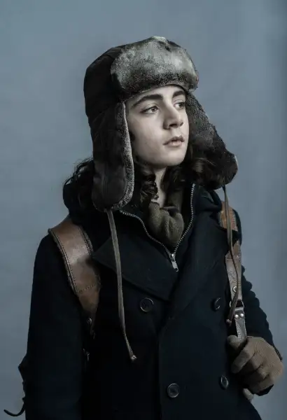FLouis Puech Scigliuzzi als Laurent Carrière in The Walking Dead: Dary Dixon. Er trägt einen schwarzen Mantel un hat einen Rucksack am Rücken. Auf dem Kopf hat er eine Fliegermütze.