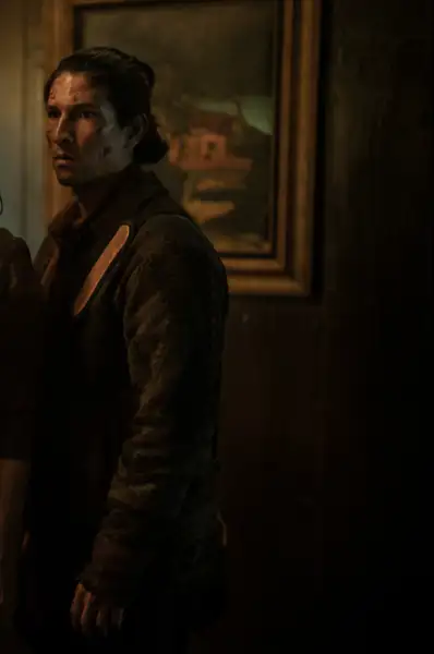 Danny Ramirez als Eric in Tales of the Waling Dead. Er trägt einen dunklen Mantel. Er ist fokussiert auf die Person mit der er redet.