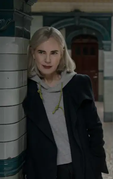 Elizabeth McGovern als Helen ain Talamasca. Sie steht in einem U-Bahn-Tunnel, lehnt sich an eine Seule. Sie trägt ein schwarzes Sakko, darunter einen silbernen Hoodie.